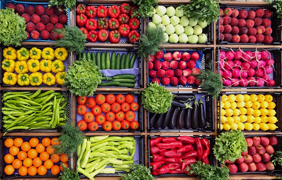 Colorful fresh produce in market crates — peppers, tomatoes, cucumbers, and more